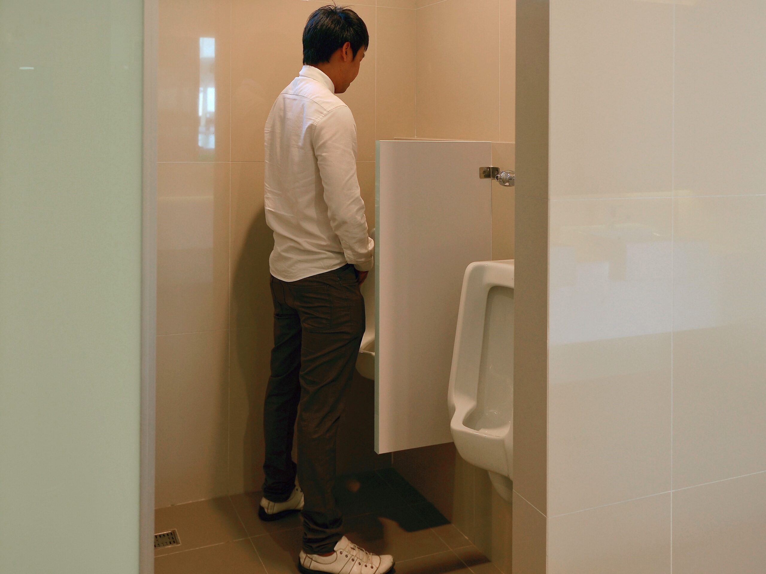 Image An Asian business man urinates in bathroom, person
